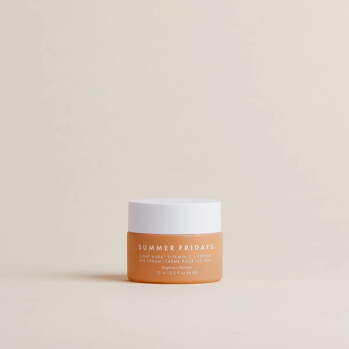 Summer Fridays Light Aura Vitamin C + Peptide Eye Cream glass jar with peachy-tinted cream